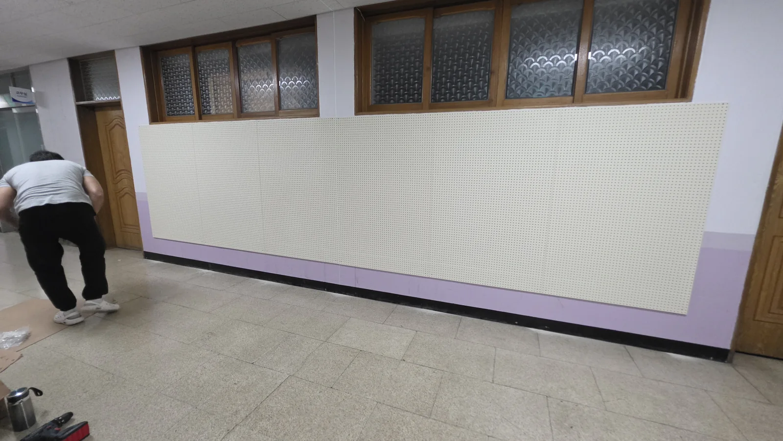 여러 장의 아이보리 타공판이 연속으로 설치된 학교 복도